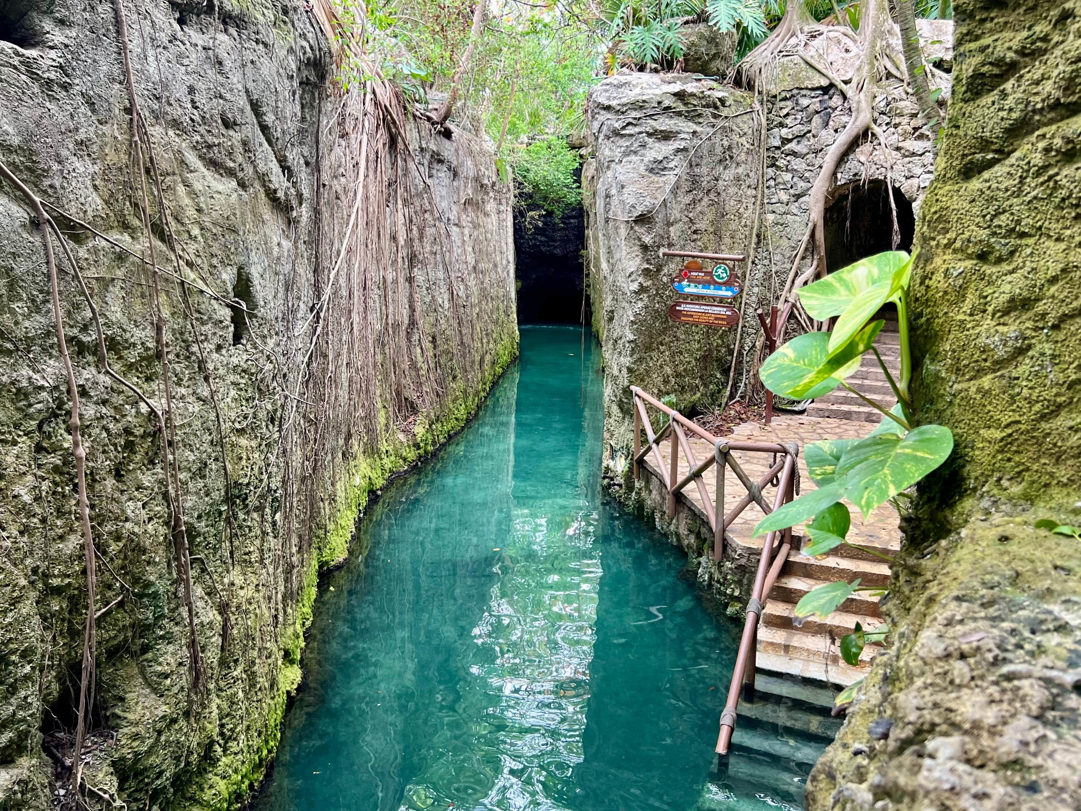 Un stretto canale d'acqua delimitato da scogliere rocciose e una passerella in legno.