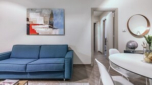 Una sala de estar moderna con un sofá azul, una mesa redonda con un globo terráqueo y un cuadro en la pared.