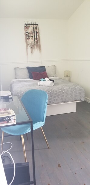 Cozy retreat with a single bed, round table, and blue chair.