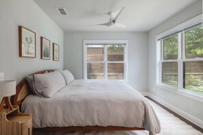 A bedroom with a bed, a ceiling fan, a window, and framed artwork on the wall. - Quintessential Zilker Bungalow (Austin)