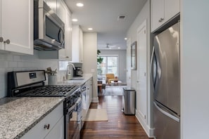 A modern kitchen with stainless steel appliances, white cabinetry, and a granite countertop. - Quintessential Zilker Bungalow (Austin)