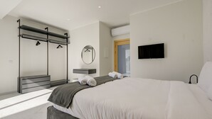 Une chambre moderne avec un grand lit, une armoire intégrée, un miroir et un téléviseur à écran plat.