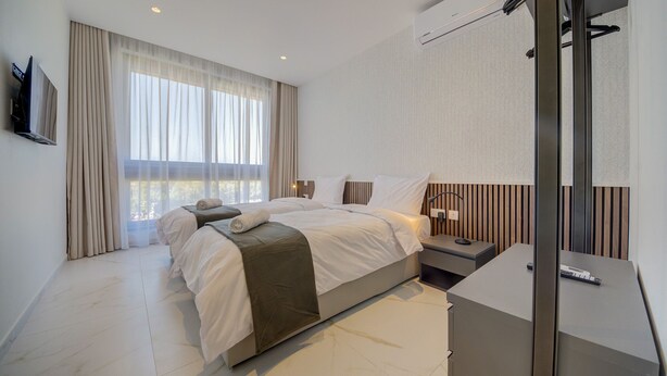 Une chambre d’hôtel moderne dotée d’un grand lit, d’un bureau et offrant une vue sur l’extérieur.