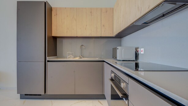 A modern kitchen with a built-in microwave, stainless steel appliances, and wooden cabinetry. - Three Bedroom Suite - Jacuzzi (Swieqi)