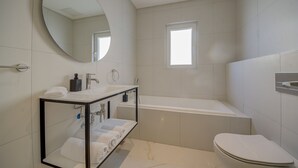 Een moderne badkamer met een badkuip, toilet en wastafel.