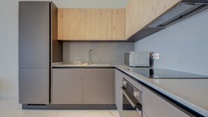 Una cucina moderna con forno a microonde integrato, elettrodomestici in acciaio inossidabile e mobili in legno.