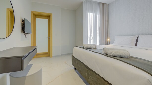 Una moderna camera d'albergo con un letto, una scrivania, uno specchio e una porta.