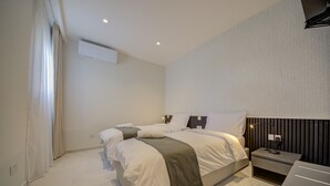 Una camera d'albergo moderna con un letto grande, comodini e un condizionatore d'aria a parete.