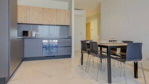 Una cucina moderna con mobili grigi, forno integrato e zona pranzo con tavolo e sedie.