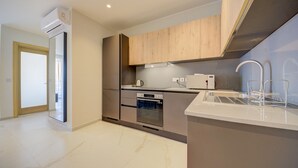 Una cocina moderna con horno empotrado, microondas y un lavabo de acero inoxidable.