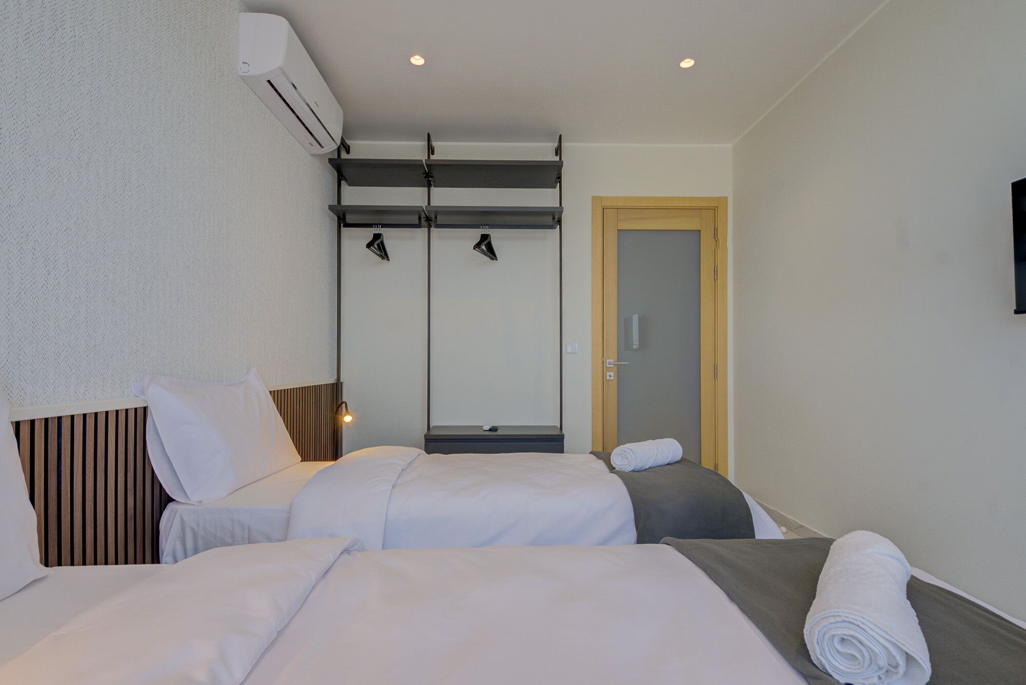 A hotel room with two beds, a wardrobe, a mirror, and a door.