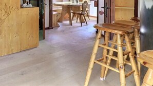 Eine Holztreppe führt zu einem Erkerbereich, einem Esstisch mit Stühlen und einem Holzschemel.