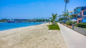 Una playa con paseo marítimo de concreto, palmeras y un edificio con balcones.