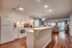 A modern kitchen with white cabinetry, a central island, and a dining area with a view.