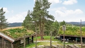 Un rustico chalet con fondamenta in pietra, circondato da una recinzione di legno e da un grande albero.