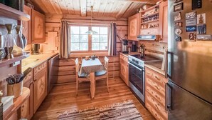 Una cucina in stile chalet con mobili in legno, un tavolo da pranzo e un frigorifero.