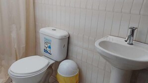 A small bathroom with a toilet, a sink, and a trash bin. - Hotel Grand Paradise Marcona (Marcona)