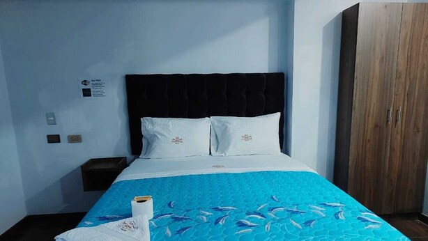 A hotel room with a bed, a wooden wardrobe, and a small nightstand. - Hotel Grand Paradise Marcona (Marcona)