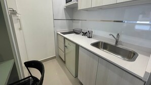 A compact kitchen with a stainless steel sink, a microwave, and a black chair. - Modern & Cozy Studio in San Telmo Num7006 (Buenos Aires)