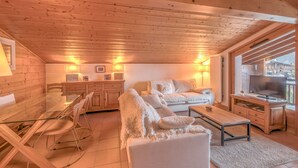 A cozy living room with a glass dining table, white sofas, and a TV on a wooden cabinet. - Appartement Denali - Welkeys (Demi-Quartier)