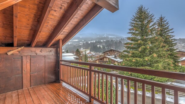 A wooden balcony with a view of a snowy mountain landscape and a pine tree. - Appartement Denali - Welkeys (Demi-Quartier)