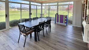 Eine überdachte Terrasse mit Esstisch und Stühlen, einem Deckenventilator und Blick ins Freie.