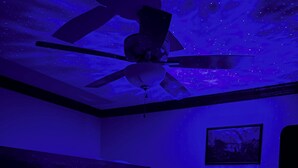 Ein Zimmer mit Etagenbett, Deckenventilator und Sternenhimmel-Projektion an der Decke.