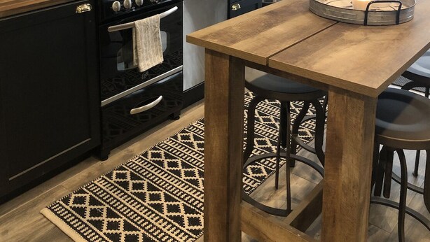 A modern kitchen with a black stove, oven, and sink, a wooden table, and a large wall clock. - Modern private suite in Vaughan (Vaughan)