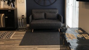 A compact living space with a sofa, a large wall clock, a television, and a kitchen area with utensils and dishes. - Modern private suite in Vaughan (Vaughan)