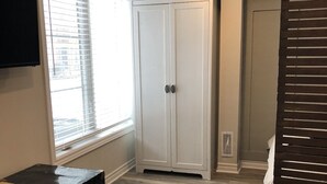 A room with a large wardrobe, a bed, a window with blinds, and a black suitcase on the floor. - Modern private suite in Vaughan (Vaughan)