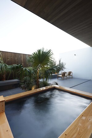 A modern outdoor pool area with wooden deck, seating, and tropical plants. - NOT A HOTEL AOSHIMA (Miyazaki)