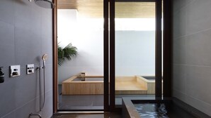 A modern bathroom with a glass shower enclosure, a wooden bathtub, and a small wooden bench. - NOT A HOTEL AOSHIMA (Miyazaki)