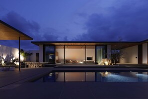 Una casa moderna con piscina, ventanas amplias y mobiliario para exteriores.