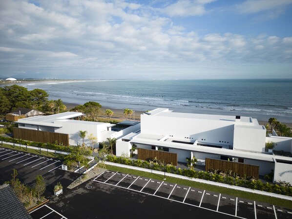 A modern building with a parking lot and a view of the ocean. - NOT A HOTEL AOSHIMA (Miyazaki)