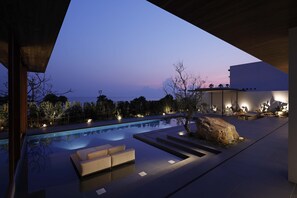 A modern outdoor pool area with a clear view of the sky, a large rock feature, and a seating area. - NOT A HOTEL AOSHIMA (Miyazaki)