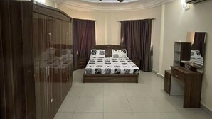 A bedroom with a bed, a wardrobe, a desk, a ceiling fan, and an air conditioning unit. - SMART DWELLINGS (Brufut)
