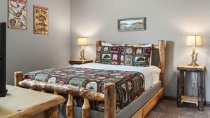 A cozy bedroom with a wooden bed frame, quilted bedding, two bedside lamps, and wall art depicting birds and fish. - Scenic Lakefront Lodge w/ Private Hot Tub, Boat Slip, Wraparound Deck & Free Attractions (Branson)