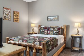 A cozy bedroom with a wooden bed frame, quilted bedding, two bedside lamps, and wall art depicting birds and fish.