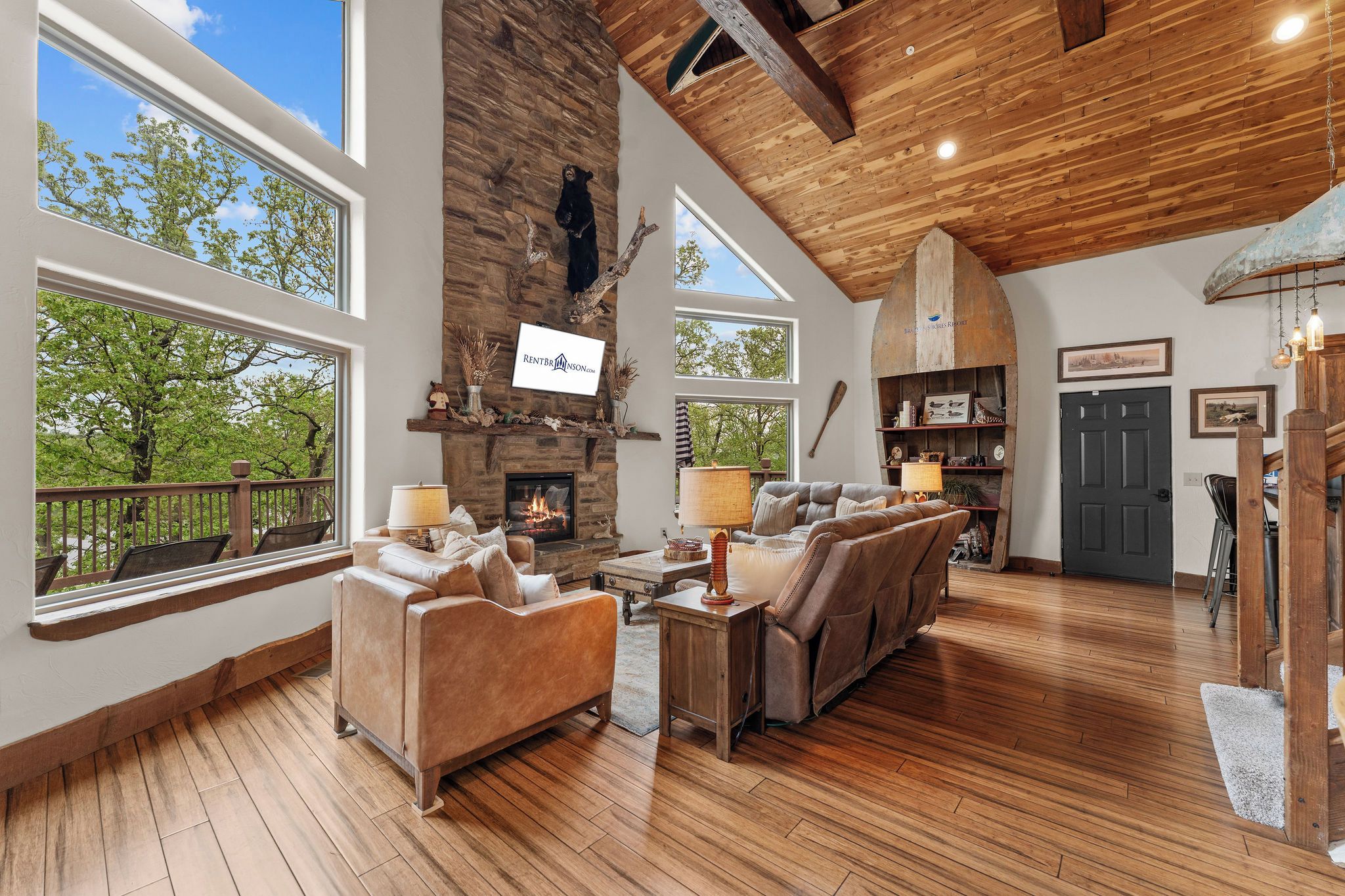 A spacious living room with a fireplace, leather sofas, and a large window overlooking greenery.