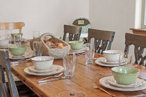 A wooden dining table set with plates, bowls, glasses, and cutlery. - Scenic Lakefront Lodge w/ Private Hot Tub, Boat Slip, Wraparound Deck & Free Attractions (Branson)
