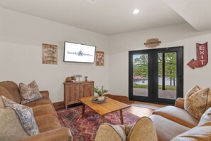 A living room with a television, a wooden cabinet, a coffee table, and a couch. - Scenic Lakefront Lodge w/ Private Hot Tub, Boat Slip, Wraparound Deck & Free Attractions (Branson)