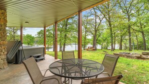 A covered patio with a grill, chairs, and a view of a lake. - Scenic Lakefront Lodge w/ Private Hot Tub, Boat Slip, Wraparound Deck & Free Attractions (Branson)