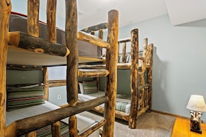 Une chambre avec un lit superposé, dotée de barrières en bois et d’oreillers à rayures.