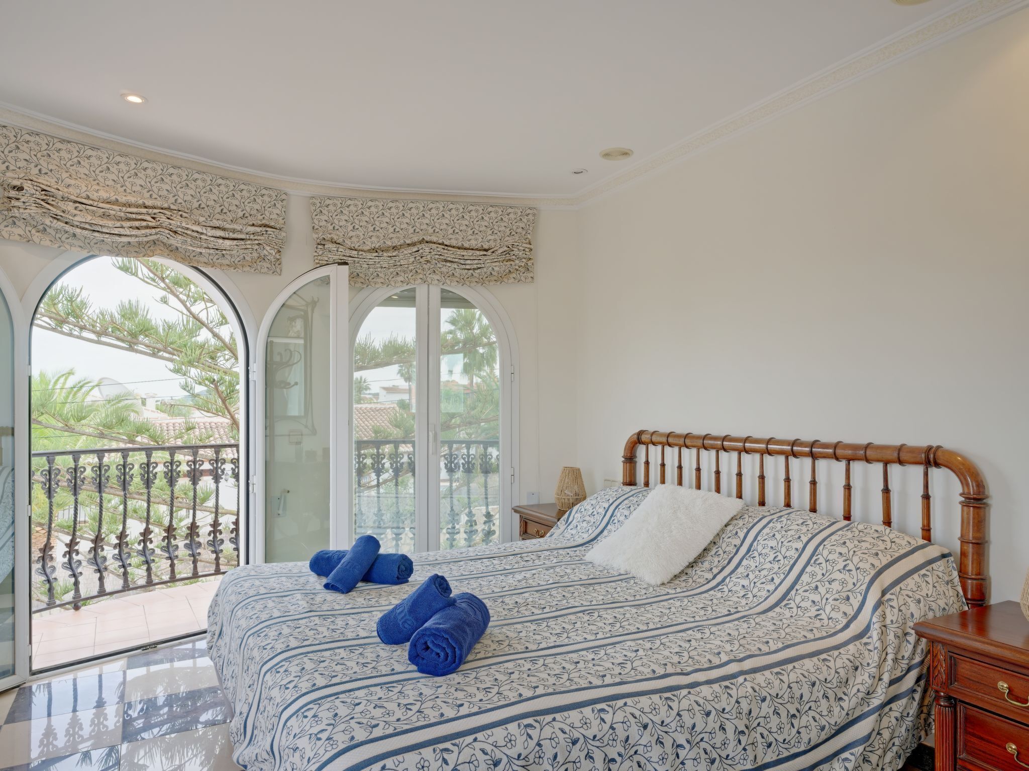 A bedroom with a large bed, a wooden headboard, and a view through a glass door to an outdoor balcony.