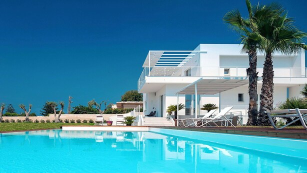 A modern two-story building with a swimming pool in front.