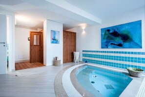 A modern indoor swimming pool with a wooden door, a large abstract painting, and a tiled wall. - Wonderful private villa with private pool, WIFI, sauna, hot tub, A/C, TV, patio and panoramic view (Marina Di Modica)