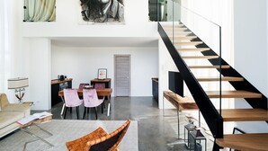 A spacious living area with a high ceiling, a modern staircase, and a dining area with a table and chairs. - Beautiful private villa for 9 people with A/C, private pool, WIFI, TV, terrace and panoramic view (Avola)