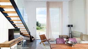 A modern living room with a wooden staircase, a TV, a dining table with chairs, a floor lamp, and a view of the outdoors. - Beautiful private villa for 9 people with A/C, private pool, WIFI, TV, terrace and panoramic view (Avola)