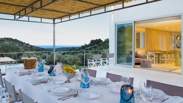 A dining table set for a meal with a view of the sea and hills. - Beautiful private villa for 9 people with A/C, private pool, WIFI, TV, terrace and panoramic view (Avola)