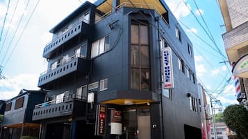 A multi-story building with a prominent 'Guest House' sign, a balcony, and a storefront with signage in a foreign language.